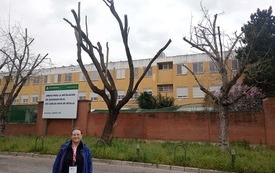 Zdjęcie nauczycielki przed budynkiem szkoły