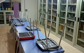 Zdjęcie biblioteki szkolnej, po środku stoją ławki, na kt&oacute;rych znajdują się krzesła