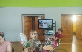 Nauczycielka siedzi przed telewizorem, prezentuje informacje o programie Erasmus