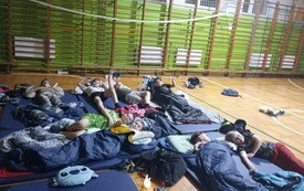 Uczniowie leżą w śpiworach na sali gimnastycznej