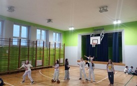 Uczennice stoją na sali gimnastycznej, trenują układ muzyczny