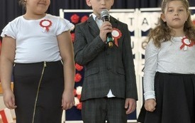 Troje uczni&oacute;w wygłasza tekst, jeden z nich trzyma mikrofon