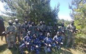 Grupa 16 uczni&oacute;w w strojach i sprzętem do paintballa