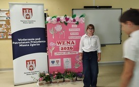 Uczennica pozuje na tle banera miasta Zgierza
