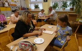 Zdjęcie sali, w kt&oacute;rej rodzice z dziećmi wykonują dekoracje na desce kuchennej