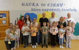 Uczniowie wraz z rodzicami pozują do zdjęcia, trzymają w rękach swoje prace