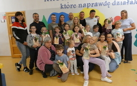 Uczniowie wraz z rodzicami pozują do zdjęcia, trzymają w rękach swoje prace