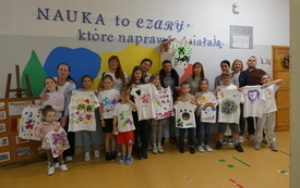 Uczniowie wraz z rodzicami pozują do zdjęcia, trzymają w rękach swoje prace