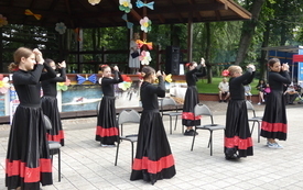 grupa dziewcząt tańczy przed sceną flamenco, ubrane są w czarne suknie