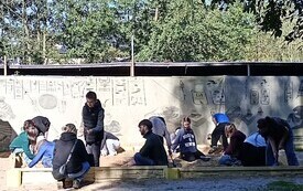 Na zdjęciu dzieci siedzą w dużej piaskownicy i szukają skarb&oacute;w