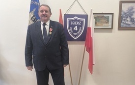 Dyrektor szkoły, stoi w gabinecie, po otrzymaniu medalu