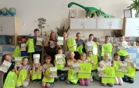 Widać uczni&oacute;w kl. 2 b, kt&oacute;rzy trzymają w rękach dyplomy z napisem "Bezpieczny uczestnik ruchu drogowego". Opr&oacute;cz dyplom&oacute;w za pracę na lekcji dzieci otrzymały r&oacute;wnież worki na buty, lub inne szkolne rzeczy. Trzymają je w rękach. Worki mają fluorescencyjny,
