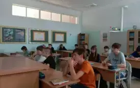 Uczniowie siedzą w ławkach i oglądają film