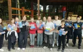 Zdjęcie grupy uczni&oacute;w  z nagrodami za rajd ekologiczny. Jeden z uczni&oacute;w trzyma pamiątkowy dyplom