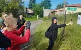 Dziewczynka zaczytuje kod QR, kt&oacute;ry wisi na siatce