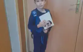 Uczeń na tle drzwi trzymający nagrodę