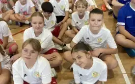 Dzieci siedzą skrzyżnie w strojach sportowych