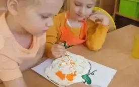 Dwie dziewczynki wyklejają dynie 