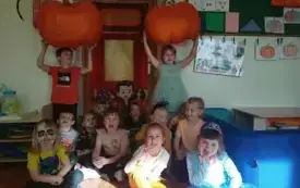 Grupa dzieci, dwoje z nich trzyma dynie