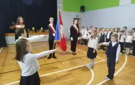 Czworo uczni&oacute;w wyciąga przed siebie rękę i wygłasza tekst ślubowania