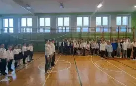 Uczniowie na sali gimnastycznej w trakcie śpiewania hymnu