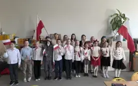 Uczniowie trzymają flagi i śpiewają hymn