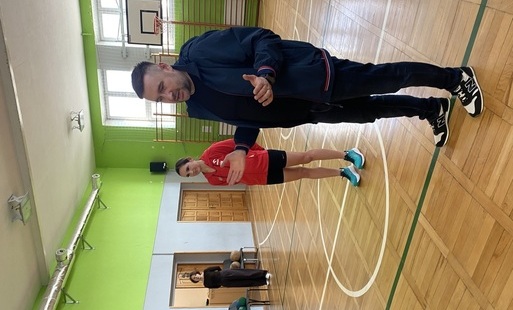 Na zdjęciu stoi mężczyzna, obok niego kobieta w sportowym stroju