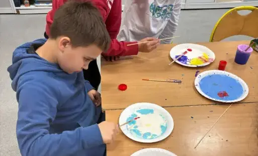 Uczeń dodaje barwnik do talerzyka  z mlekiem