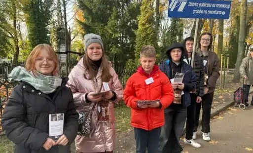 6 uczniów stoi na cmentarzu z puszkami i ulotkami