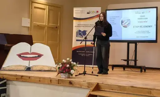 Uczennica recytująca wiersz na scenie