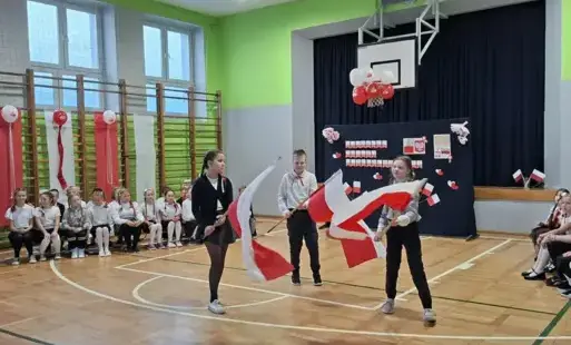Troje uczniów trzyma flagi narodowe