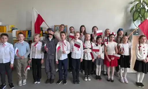 Uczniowie trzymają flagi i śpiewają hymn