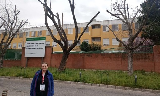 Zdjęcie nauczycielki przed budynkiem szkoły