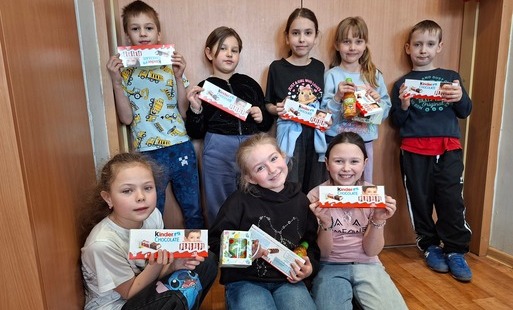 Kilkoro dzieci pozuje do zdjęcia, w ręku trzymaja czekoladki